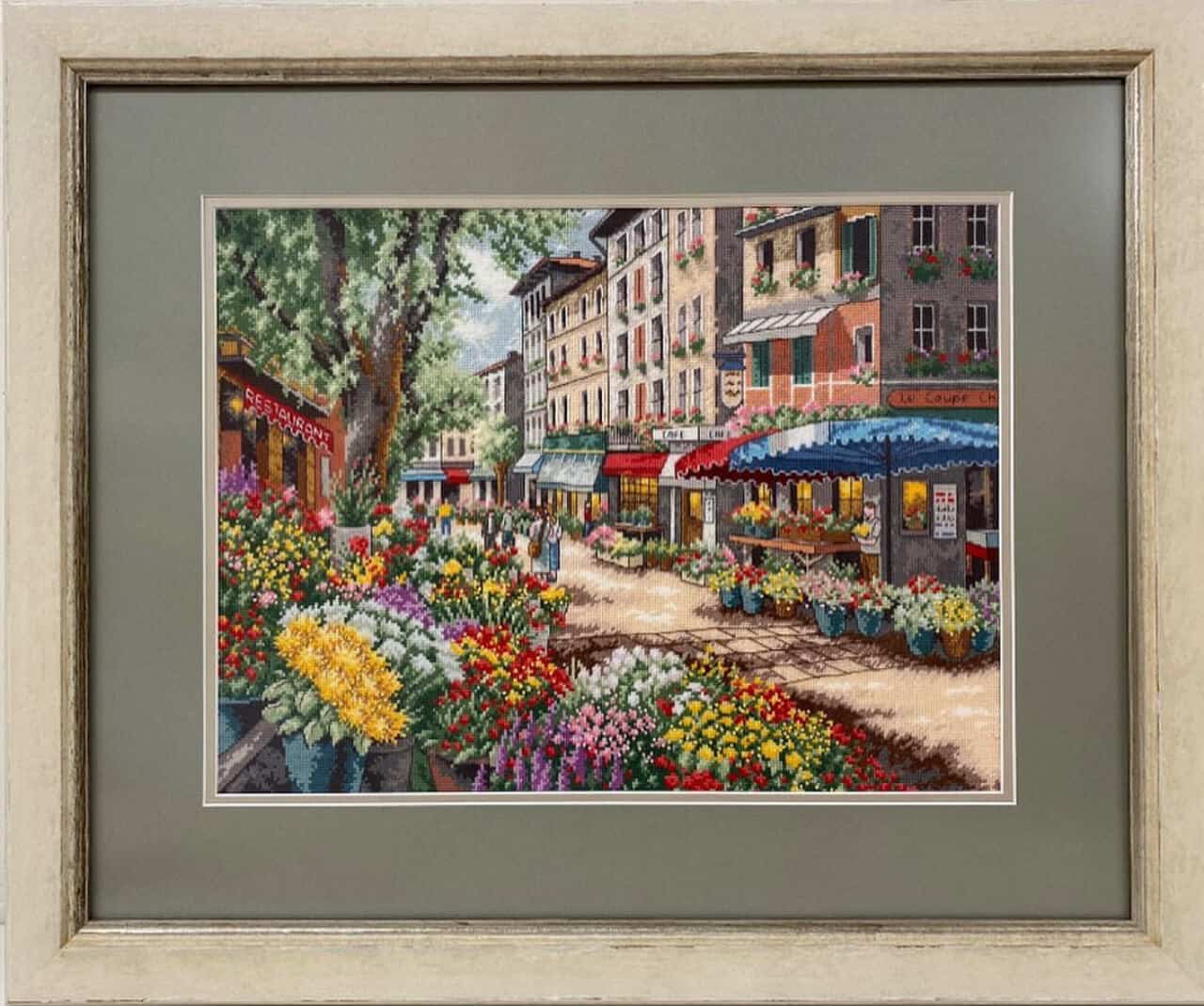 A framed cross-stitch of a flower market in paris.