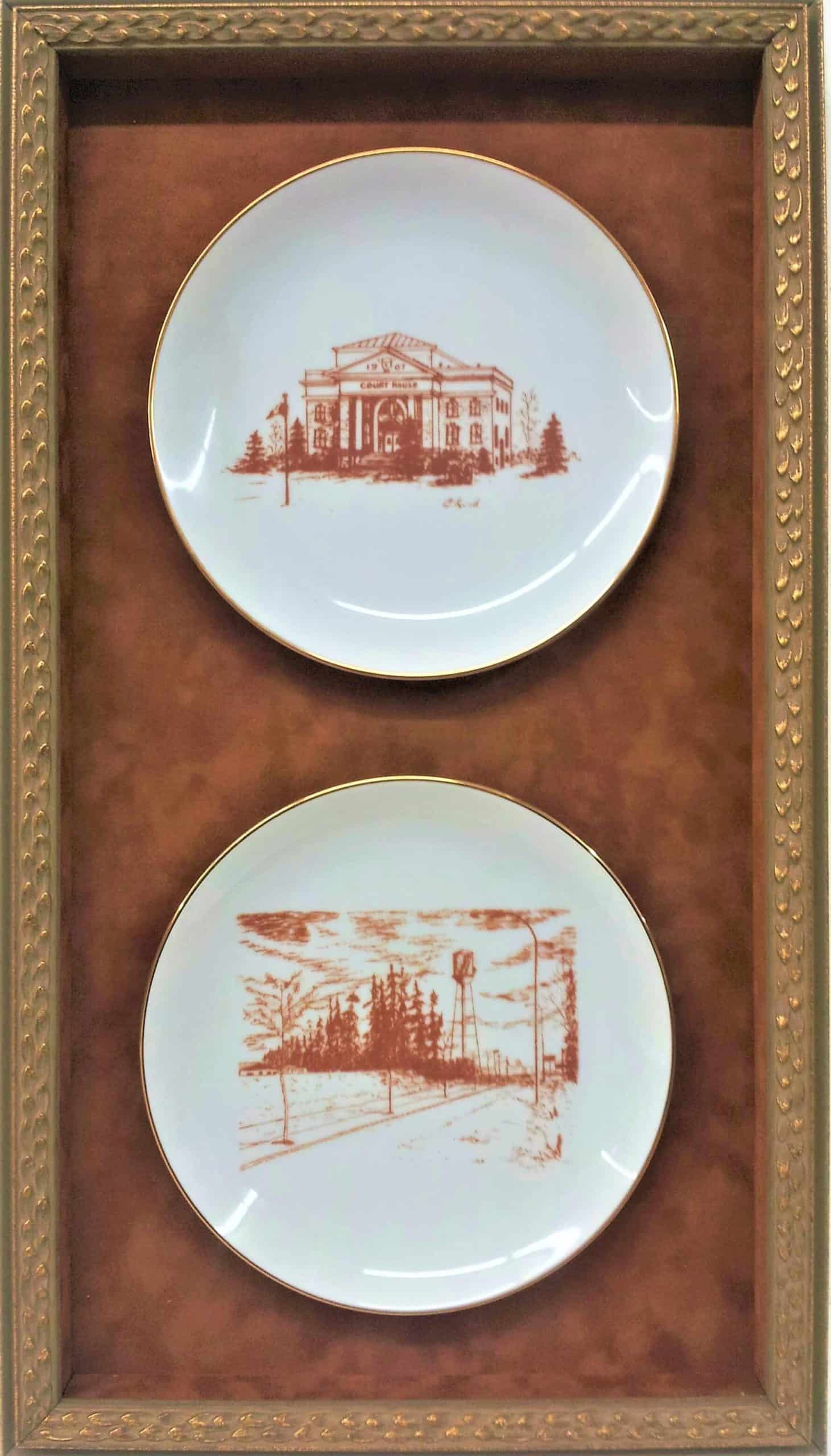 Two plates in a gold frame with a picture of a building.