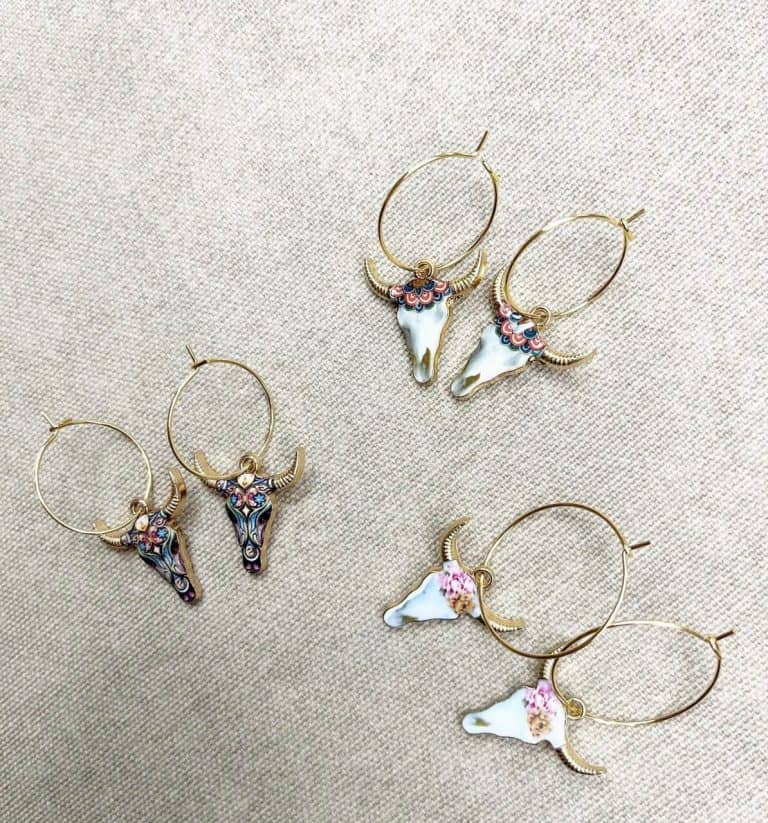A pair of gold hoop earrings with cow skulls on them.