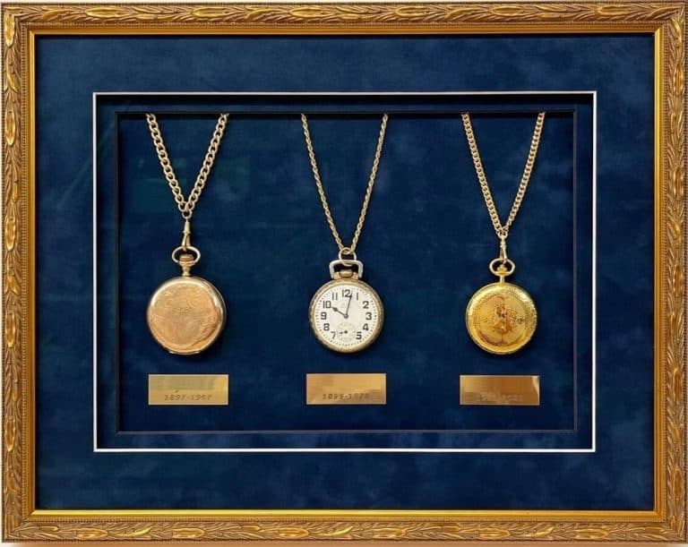 Three antique pocket watches in a framed display.